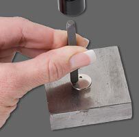Metal blank being stamped on a steel block